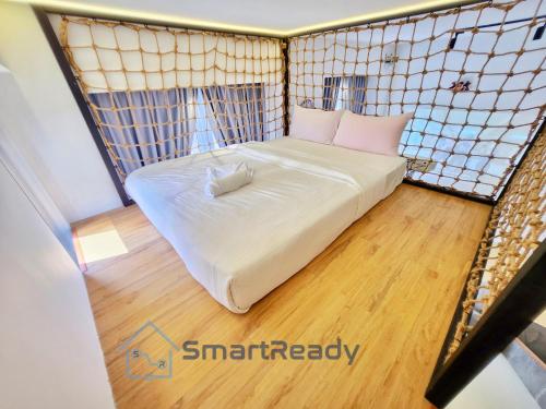 a small room with a white bed and wooden floors at Sunway GRID by SR Home in Kampong Pendas