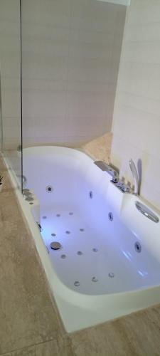 uma banheira branca com um chuveiro num quarto em El susurro del tajo La gruta em Toledo