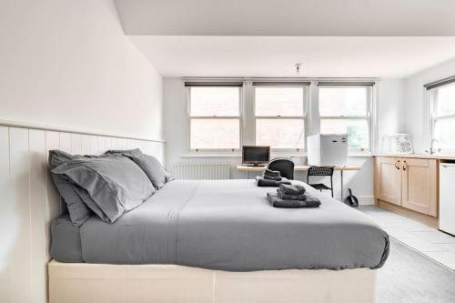 a white bedroom with a large bed and a desk at Finchley Road Studio 13 in London