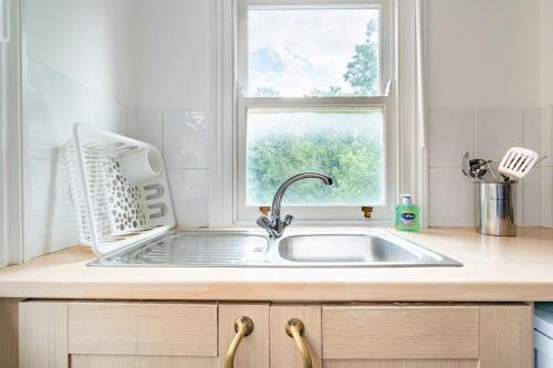um balcão de cozinha com um lavatório e uma janela em Finchley Road Studio 13 em Londres