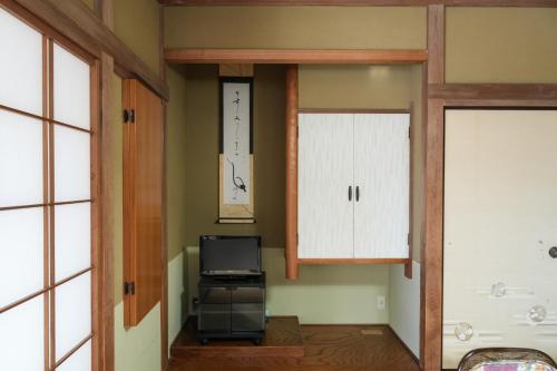 a living room with a tv and a cabinet at HOTEL LT Kitchen Yugawara in Yugawara