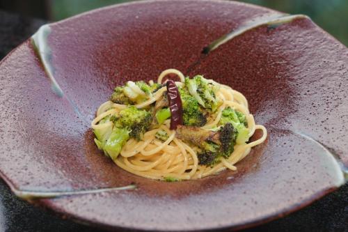 a plate of pasta and broccoli on a plate with tongs at HOTEL LT Kitchen Yugawara in Yugawara