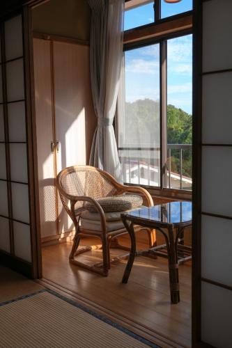 a room with a chair and a table and a window at HOTEL LT Kitchen Yugawara in Yugawara