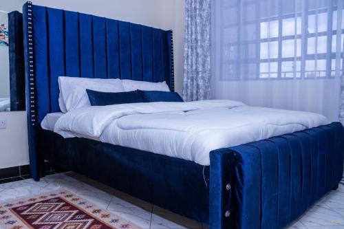a large bed with a blue headboard in a bedroom at Tiny Haven executive one bedroom with Private Balcony in Nanyuki