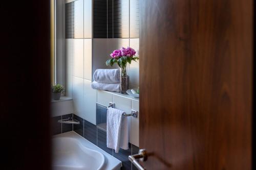 ein Badezimmer mit einem Waschbecken und einer Vase aus Blumen in der Unterkunft Art Hotel in Slavonski Brod