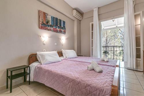 a bedroom with a bed with a pink blanket at Alexandros Apartments in Ipsos