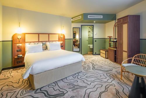 a bedroom with a large white bed and a table at voco Paris - Porte de Clichy by IHG in Clichy