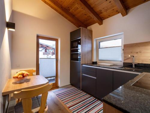 a kitchen with black cabinets and a wooden table at Ferienwohnung HOAMAT in Going