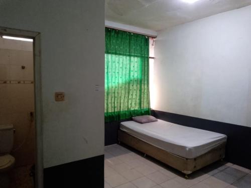 een kleine slaapkamer met een groen raam en een bed bij Penginapan 21 By SPAZIE in Jakarta