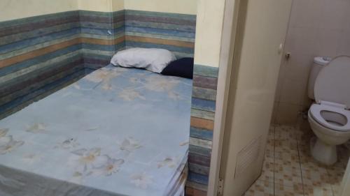 een klein bed in een badkamer met een toilet bij Penginapan 21 By SPAZIE in Jakarta