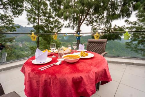 a red table with a bowl of food and wine glasses at The Golden Sunrise Hotel in Nainital