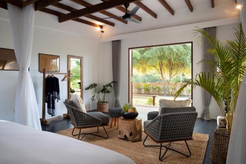 a bedroom with two chairs and a large window at Pondok Santi Estate in Gili Trawangan