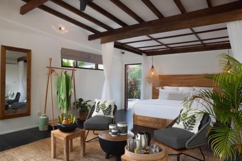 a bedroom with a bed and two chairs and a mirror at Pondok Santi Estate in Gili Trawangan