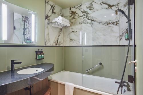 a bathroom with a tub and a sink and a shower at voco Paris - Porte de Clichy, an IHG Hotel in Clichy