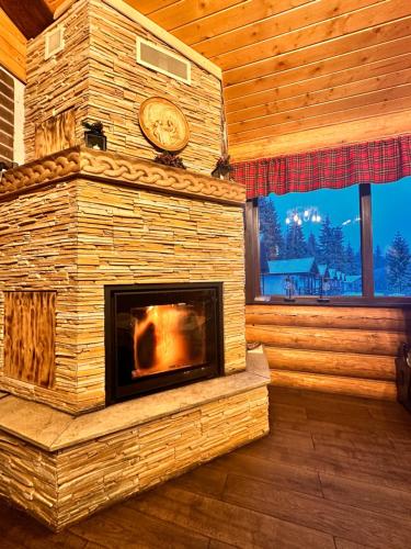 a fireplace in a log cabin with a clock on it at CLUBUL DACILOR in Comandău