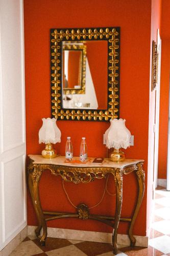 a table with a mirror on a red wall at Martins Residence de Luxe in Ravenna
