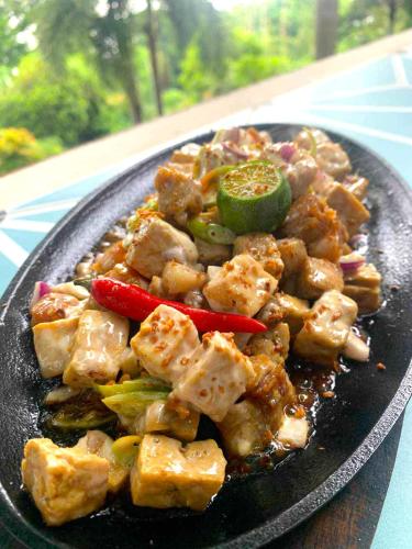 a plate of food with meat and vegetables on a table at Villas by Eco Hotels in Mataasnakahoy