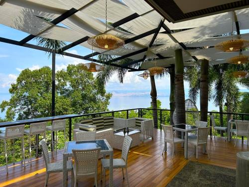 a patio with tables and chairs and a view of the water at Villas by Eco Hotels Batangas in Mataasnakahoy