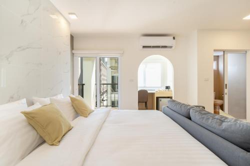 a large white bed with yellow pillows in a room at Diya Hotel Bangkok in Amphoe Phra Khanong