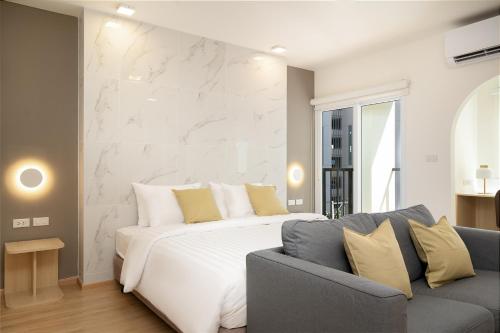 a bedroom with a white bed and a couch at Diya Hotel Bangkok in Amphoe Phra Khanong