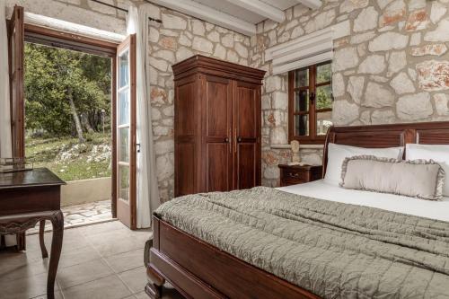 a bedroom with a bed and a stone wall at Villa Boscheto Tria in Agios Leon