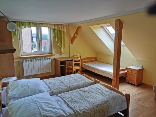 1 dormitorio con 2 camas, escritorio y ventana en Willa Hamernik AGROTURYSTYKA, en Tylicz