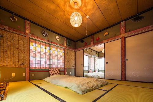 ein Schlafzimmer mit einem Bett in einem Zimmer mit Fenstern in der Unterkunft I LOVE HANEDA in Tokio