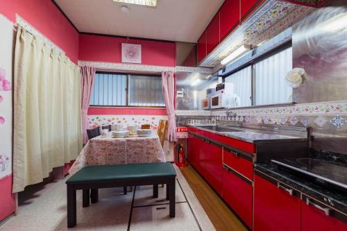 a kitchen with red cabinets and a table in it at I LOVE HANEDA in Tokyo