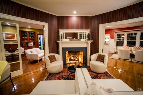 a living room with a fireplace and white chairs at Lindenwood Inn in Southwest Harbor