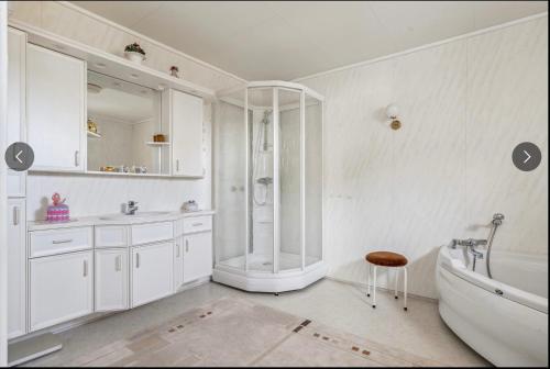 a white bathroom with a shower and a tub at Skipperhuset in Sund