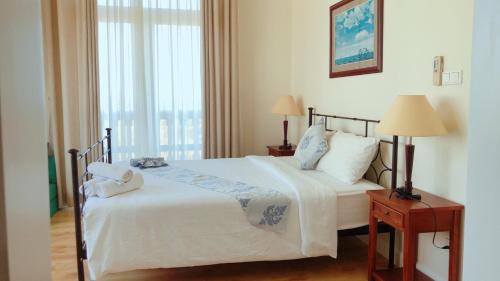 a bedroom with a bed with two lamps and a window at Sealink Beach Villa PE48- PE69 in Ấp Bình Hưng