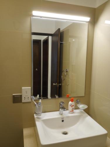 a bathroom with a white sink and a mirror at OCEAN BREEZE - WAVES LUXURY CONDO in Negombo