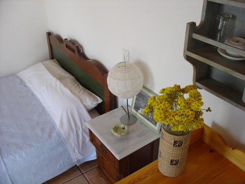 ein Schlafzimmer mit einem Bett und einem Tisch mit einer Lampe und Blumen in der Unterkunft Kyma sto Phos in Folegandros Chora