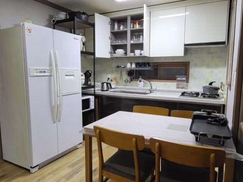 a kitchen with a white refrigerator and a table with chairs at Donghae sea hill House in Yŏngdŏk