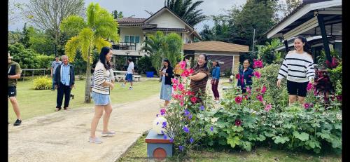a group of people standing around a garden at Panutsaya Homestay in Wang Nam Khieo