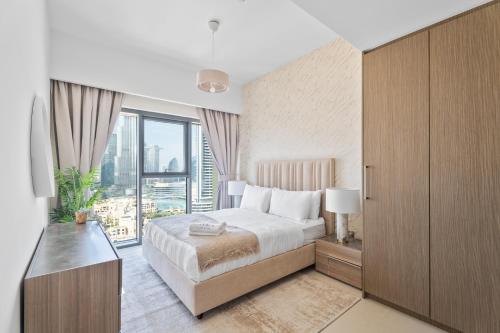 een slaapkamer met een bed en een groot raam bij Nasma Luxury Stays - Burj Royale 2BR Apartment in Downtown With Views in Dubai