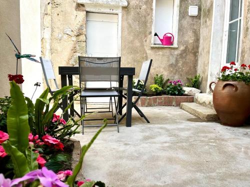 une terrasse avec une table noire, des chaises et des fleurs dans l'établissement Appartement situé au cœur des belles ruelles sablaises - 5 pers, à Les Sables-dʼOlonne