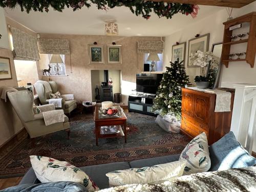 a living room with a christmas tree and a couch at Turnpike Cottage in Tetbury