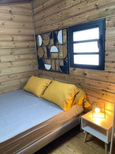a bed in a log cabin with a window at Tiny house bois cosy « Halte là » in La Possession