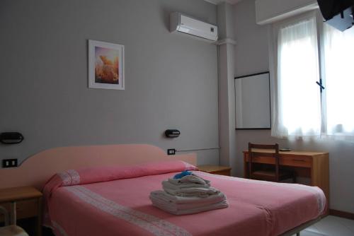 a bedroom with a bed with pink sheets and a window at Hotel Laura Beach in Rimini