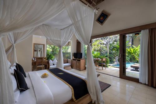 a bedroom with a bed and a living room at The Sankara Resort by Pramana in Ubud