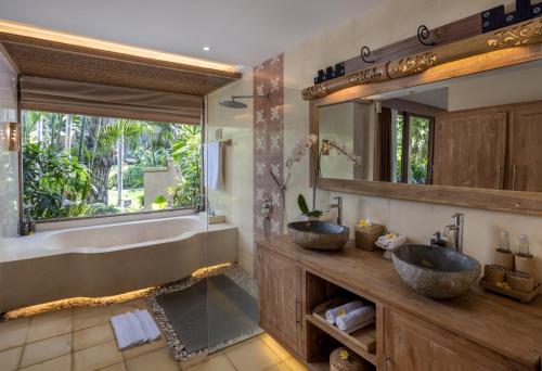 two sinks in a bathroom with a tub and a mirror at The Sankara Resort by Pramana in Ubud