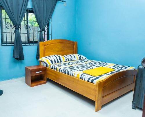 a bedroom with a wooden bed with a blue wall at Vyemma Residence in Limbe