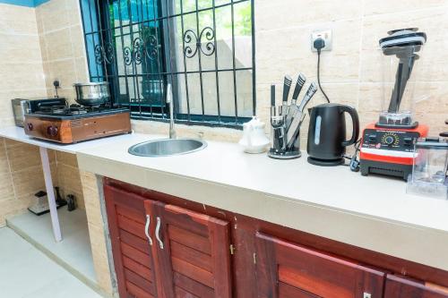 a kitchen counter with a sink and a stove at Vyemma Residence in Limbe