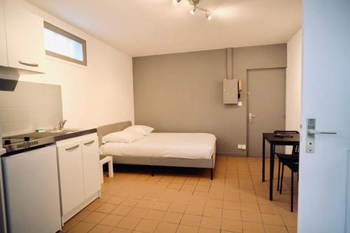 une petite pièce avec un lit et une table dans l'établissement Canal Varignon, à Caen