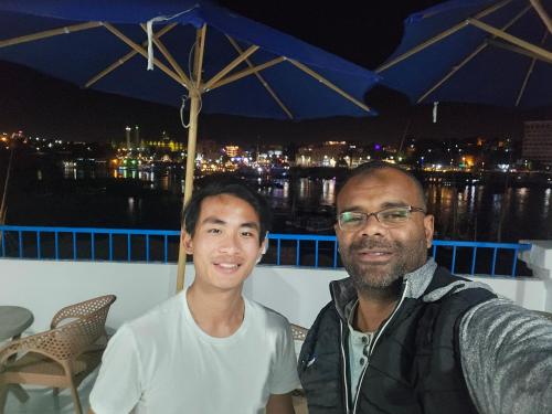 two men sitting on a balcony with an umbrella at La Terrace in Aswan