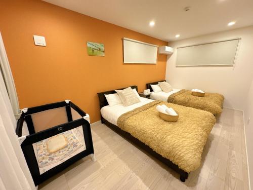 two beds in a room with orange walls at グランディオーソ沖縄プールヴィラ恩納7 in Onna