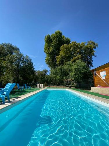 une grande piscine avec des chaises bleues et des arbres dans l'établissement Le Moulin de César, à Vaison-la-Romaine