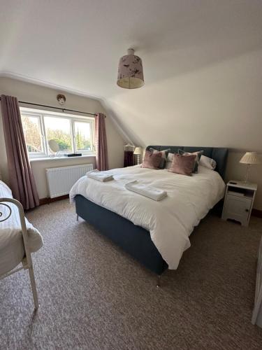 a bedroom with a large bed and a window at Turnpike Cottage in Tetbury