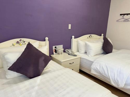 two beds in a room with purple walls at Bei Ao Bi Shan Jyu in Dongyin